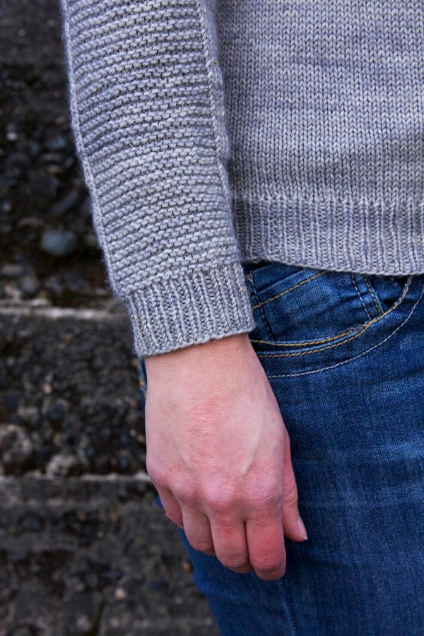 cuff of a grey sweater with garter stitch panel