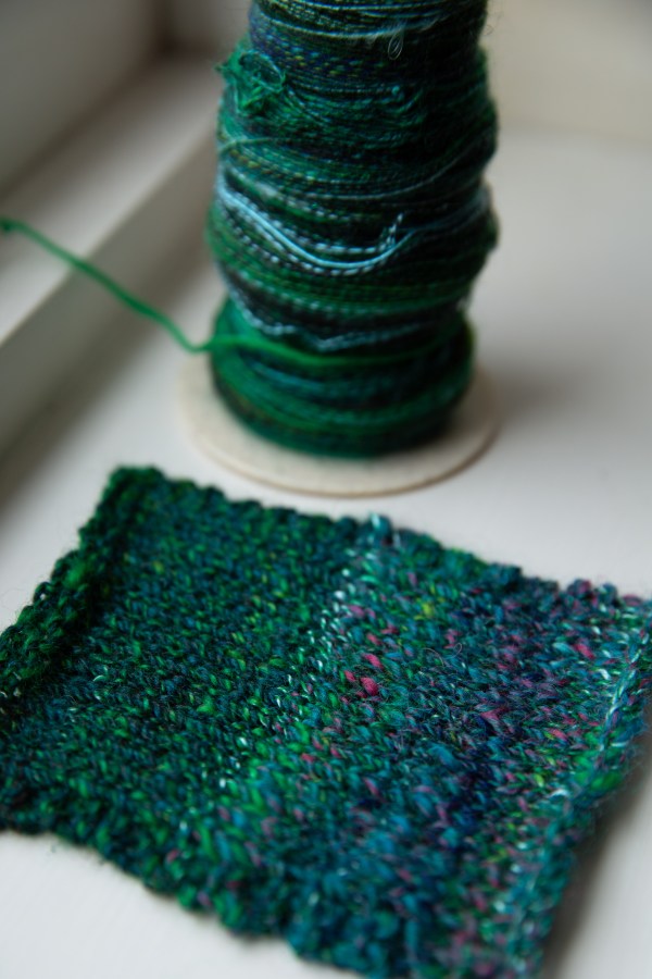 bobbins of green singles and a knit swatch
