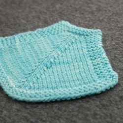 A pale blue swatch with a strong decrease line. The decreases slant towards a central stitch. 
