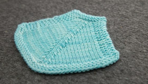 A pale blue swatch with a strong decrease line. The decreases slant towards a central stitch. 